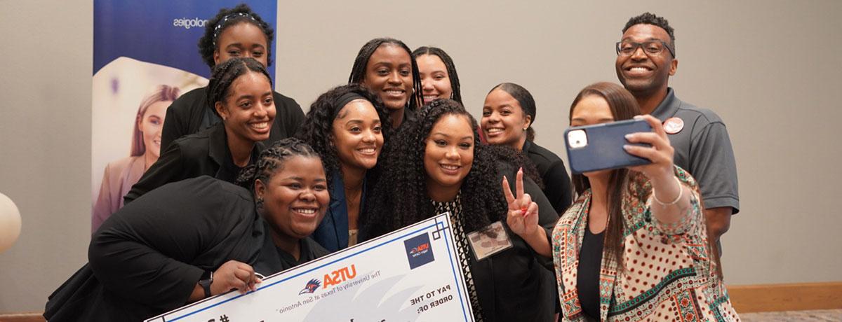 Students taking a photo with the check they won